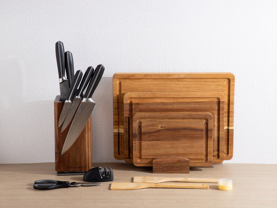 BAUER & MEYER Chef's Choice Collection: messenblok met zwarte messen naast acaciahouten snijplanken in houder